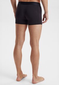 Schwarze Baumwollstretch-Boxershorts mit glattem Bund, taillierter Passform und mittellanger Beinlänge, die eine schlichte, minimalistische Silhouette präsentieren.