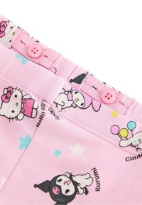 Tissu rose avec des motifs de personnages de dessins animés, comprenant Hello Kitty et d'autres. Comprend une taille avec des boutons roses et des petits motifs d'étoiles.