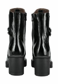 Bottines en cuir verni noir avec un talon épais, dotées de fermetures éclair sur les côtés et d'un détail de sangle avec une boucle sur chaque botte.