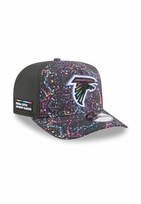 Casquette noire avec un motif éclaboussé coloré, logo brodé à l'avant et une étiquette sur le côté indiquant "CRUCIAL CATCH INTERCEPT CANCER."