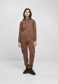 Brun fleece hettegenser med kengurulomme og justerbare snorer, parret med matchende cargo-bukser med sidelommer og tettsittende mansjetter.