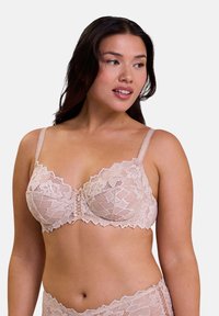 Reggiseno in pizzo color nude con supporto a stecche, bordi scallop e centro decorativo. Spalline lisce e motivo floreale in pizzo intricato su tutta la superficie.