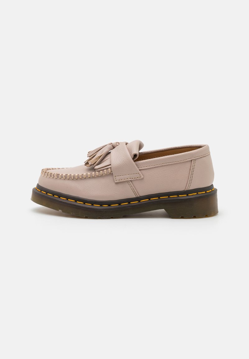 Mocassins en cuir beiges avec détail en pampille, couture moccasin, et épaisse semelle translucide avec couture jaune sur fond blanc.