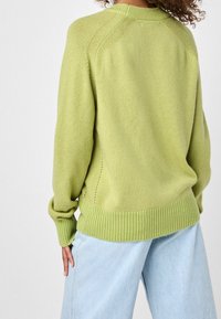 Pull en tricot vert clair avec un ourlet et des poignets côtelés, doté d'un col rond et de manches raglan, texture lisse et épaisseur moyenne.