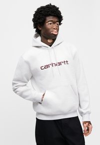Ανοιχτό γκρι φούτερ με κουκούλα από υφασμάτινη υφή με μπροστινή τσέπη. Διαθέτει μπορντό λογότυπο "carhartt." στο κέντρο του στήθους.