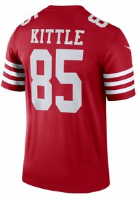 Piros sportmez rövid ujjakkal. Fehér csíkok és nagy betűs feliratok találhatók rajta: "KITTLE" és "85" a hátsó részen. Simább textúrájú.