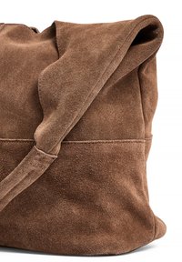 Brown suede bag with a soft texture, featuring a fold-over top and side stitching details, conveying a casual, relaxed design.