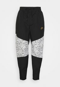 Černé joggingové kalhoty s bílou panelem s paisley vzorem. Obsahují elastický pas, šňůrku na stažení a zlatý akcent s logem.