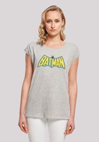 Hallide hallist puuvillane T-särk lühikeste varrukatega ja ümar kaelus, mille ees on sinine ja kollane "BATMAN" graafika.