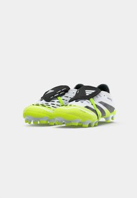 Crampons de football blancs et jaune néon avec des détails noirs et des protections noires pour les lacets, positionnés côte à côte sur un fond blanc.