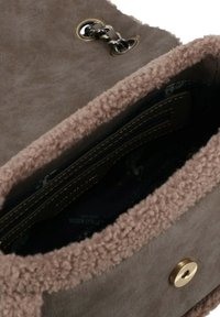Borsa in suede marrone con bordo in morbido e testurizzato shearling. Presenta una chiusura con bottone color oro e una tasca interna con zip.