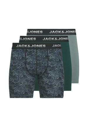 Drie paar herenboxershorts: één met een donker bladmotief, één in groen en één in lichtgrijs. Allemaal met zwarte, gebrande taillebanden.