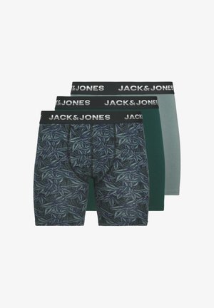 Drie paar herenboxershorts: één met een donker bladmotief, één in groen en één in lichtgrijs. Allemaal met zwarte, gebrande taillebanden.
