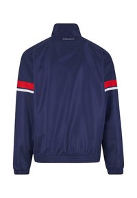 Navy sininen tuulenpitävä takki, jossa on korkea kaulus, joustavat hihansuut ja vyötärö. Olkasaumassa punaisia ja valkoisia raitoja. Sujuva texture.