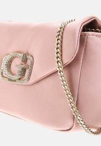 Borsa sintetica rosa con una tracolla a catena, caratterizzata da una placca logo impreziosita da cristalli sulla patta e una superficie liscia.