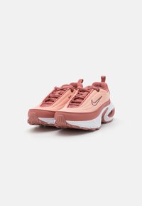 Sapatilhas Nike com parte superior em malha de rosa claro e coral, apresentando detalhes texturizados, uma entressola branca e um design de sola acolchoada distintivo.