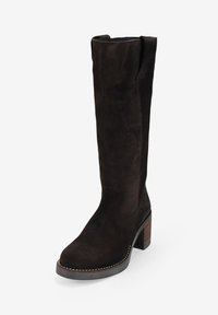 Bota alta hasta la rodilla de ante marrón con punta redondeada, tacón bloque, detalle de costura lateral y lazo en la parte superior para facilitar su uso.