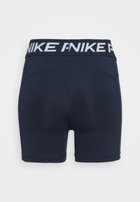 Shorts de sport bleu marine avec une large ceinture présentant un texte blanc répété "NIKE", vus de dos sur un fond uni.
