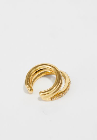 Guld metalring med en poleret finish, der har et buet design og en sektion dekoreret med små klare rhinsten.