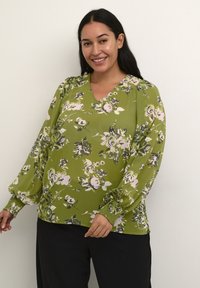 Grøn blomsterbluse med V-hals, lange puffærmer og rynkede manchetter. Fremtrædende mønstre af pink og hvide blomster med mørke detaljer.