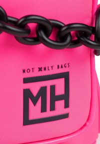 Bolso de nailon rosa con acentos de cadena negra, presenta un logotipo en relieve con el texto "NO SOLO BOLSOS" y forma rectangular. Textura suave.