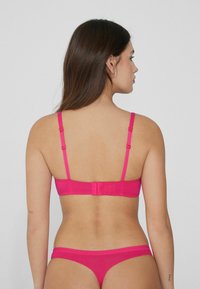 Conjunto de sujetador y tanga rosa con tirantes ajustables, material suave y cierre de gancho en la parte posterior. Diseño sencillo y textura suave.