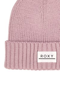 Berretto a maglia color rosa chiaro, con una visiera ripiegata a coste e un'etichetta bianca con testo nero che dice "ROXY." Texture morbida, forma arrotondata.