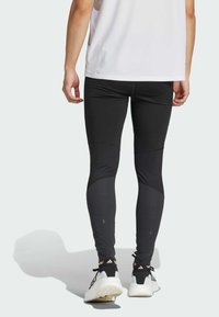 Leggings deportivos negros con un diseño ajustado, que presentan paneles de tela en contraste, acentos texturizados y un acabado elegante.