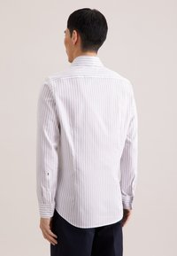 Gestreept shirt met lange mouwen in lichtgrijs en wit, voorzien van een licht gebogen zoom, knoopdetails op de manchetten en een klassieke kraag.