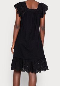 Vestito nero con maniche corte arricciate, vestibilità ampia e orlo smerlato con dettagli a occhiello. Realizzato in tessuto leggero.