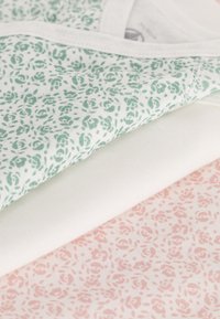 Drie lagen katoenstof: één in mintgroen met rozenpatroon, één plain wit, en één pastelroze met rozenpatroon.
