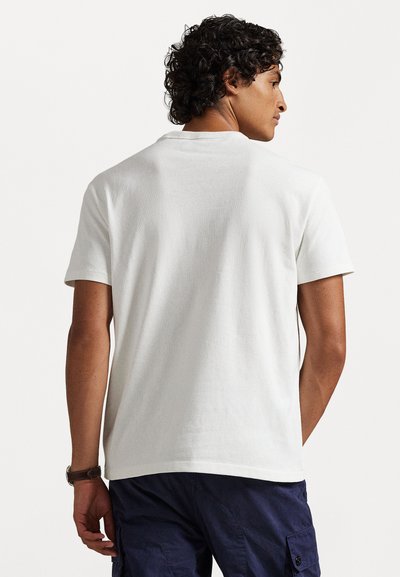 Μπλουζάκι κοντομάνικο, με στρογγυλή λαιμόκοψη, σε μαλακό και ελαφρύ λευκό βαμβάκι, με απλό σχέδιο και άνετη εφαρμογή, βλεπόμενο από πίσω.