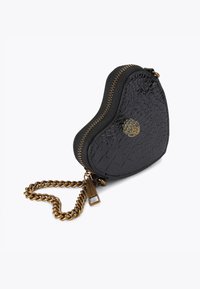 Sac en forme de cœur en simili cuir noir avec texture crocodile, ferrures dorées, fermeture éclair, et une bandoulière en chaîne dorée.