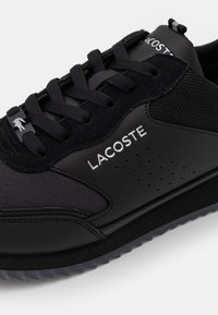 Schwarzer Sportschuh aus Mesh und synthetischen Materialien. Verfügt über ein strukturiertes Design, Schnürverschluss und metallisches Logodetail.