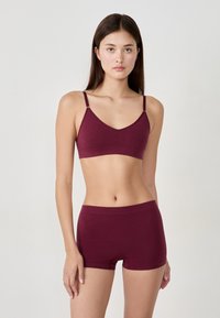 Bordowy biustonosz braletka z cienkimi ramiączkami i dekoltem w kształcie litery V, w komplecie z dopasowanymi krótkimi majtkami. Miękki, elastyczny materiał bez szwów.
