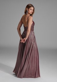 Pitkä, laskostettu mekko syvän burgundin värisestä kankaasta, jossa on himmeä pinta. Ominaisuuksiin kuuluvat ohuet hihnat ja matala selkäosa, jotka luovat virtaavan siluetin.