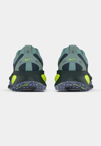 Αθλητικά παπούτσια Nike σε πράσινο και ναυτικό μπλε με φωσφοριζέ κίτρινες λεπτομέ�ρειες, με υφασμάτινη σόλα και αναπνέον πλέγμα επάνω, καθώς και επενδεδυμένο κολάρο στη φτέρνα.