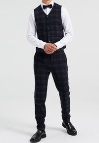 Marinblått rutigt tredelat kostym med gröna och vinröda accenter. Innehåller en väst med v-ringning, knäppning och svarta finskor. Strukturerad tyg.