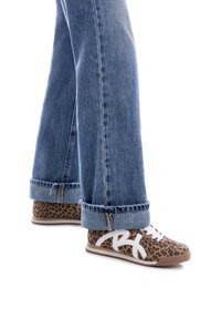 Zapatillas de print de leopardo con detalles en blanco y marrón claro, con un diseño de cordones y suela de goma, combinadas con jeans de denim claro.