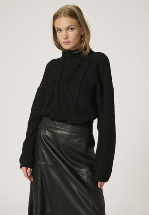 Black knitted sweater with a high neck and textured detailing, paired with a black leather midi skirt featuring a smooth finish.