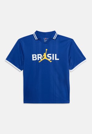 Camiseta deportiva azul de manga corta con texto blanco "BRASIL" y logotipo amarillo de Jumpman centrado, cuello con rayas blancas y bordes blancos en las mangas.