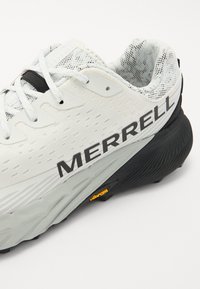 Chaussure de sport blanche avec tige en mesh, accents noirs et grand logo "MERRELL". Semelle extérieure Vibram remarquable pour traction et durabilité.