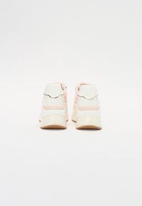 Urheilukengät, joissa valkoinen pohja, vaaleanpunaiset tehosteet, teksturoidut kangaspaneelit ja pehmustettu kaulus, litteällä kumipohjalla ja sahalaitakuvioinnilla.