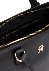 Black leather handbag with gold hardware, featuring a zippered interior and multiple pockets for organization. Textured finish, minimal branding.