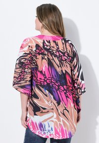 Top over-size multicolore con un motivo astratto fluido nei toni del rosa, nero e beige. Tessuto morbido con maniche ampie e orlo arrotondato.