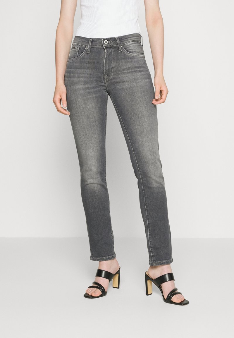 Tajta grå denimjeans med midjehög midja, fem fickor och subtila slitningar, tillsammans med svarta högklackade sandaler.