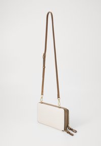 Sac bandoulière couleur crème en cuir lisse, de forme rectangulaire, avec une sangle brune réglable et des accents en métal doré.