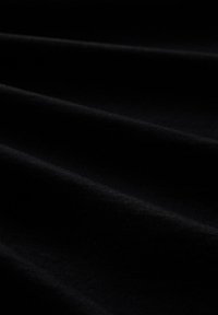 Zwarte stof met een gladde textuur, gekenmerkt door gevouwen plooien en subtiele variaties in licht, waardoor de diepte en zachtheid benadrukt worden.