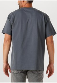 Szara bawełniana koszulka z krótkim rękawem, okrągłym dekoltem i luźnym krojem. Materiał wydaje się gładki i lekki.