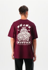 Maroon cotton t-shirt with oversized fit, featuring a white floral graphic and Japanese text on the back, short sleeves, and crew neck.